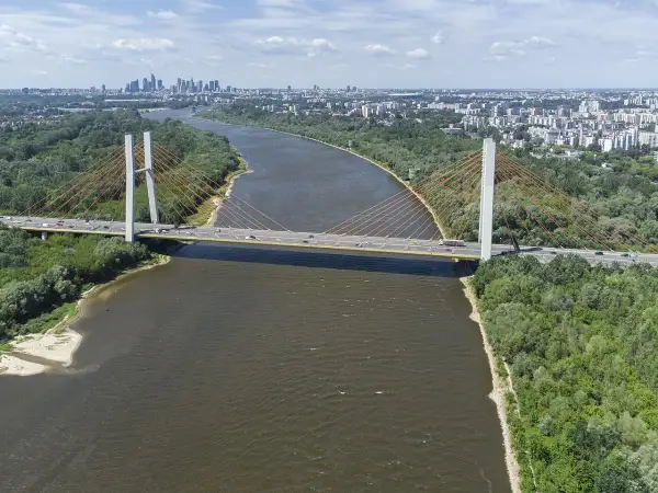 Most Siekierkowski w Warszawie nad Wisłą, z widokiem na panoramę miasta i zielone brzegi.