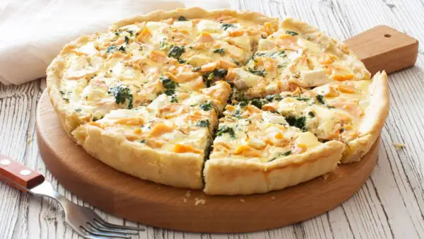 Tarta de espinacas y salmón, recién horneada y cortada en porciones, lista para disfrutar.