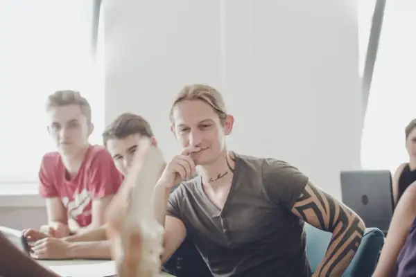 Junge Männer im Gespräch, einer mit Tattoos, vielleicht beim bachelor physiotherapie berufsbegleitend.