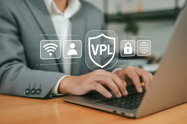 Osoba pracuje na laptopie, a nad klawiaturą wyświetlają się ikony symbolizujące bezpieczeństwo online, w tym tarcza z napisem VPL. Dowiedz się, vpn jak włączyć, by chronić swoją prywatność.