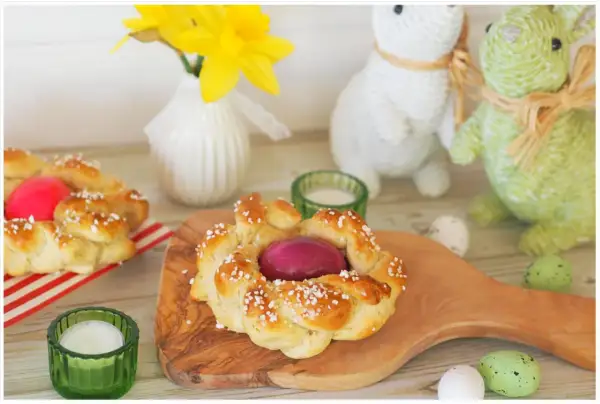 Zwei geflochtene Osterkränze mit gefärbten Eiern, bereit zum Osterfrühstück. Das Backen von Osterkränzen ist eine schöne Tradition.