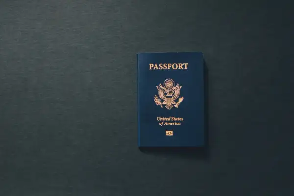 Niebieski paszport USA leży na ciemnym tle. Dokument przypomina o tym, ile ważny jest paszport dla podróżujących.