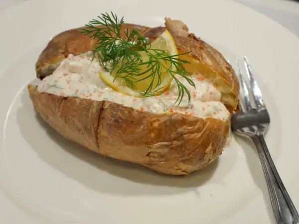En saftig bakad potatis fylld med en krämig röra med rom, dill och citron. En gaffel ligger bredvid.