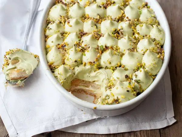 Un cremoso tiramisù al pistacchio, guarnito con granella di pistacchi, pronto per essere gustato.