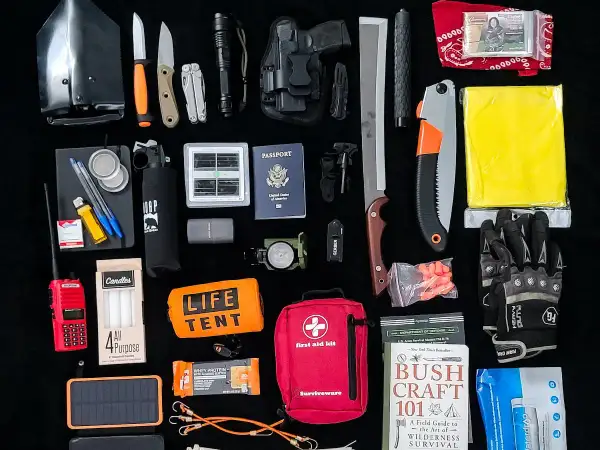 Un conjunto de herramientas EDC para supervivencia: pala plegable, cuchillos, linterna, multiherramienta, pistola, brújula, kit de primeros auxilios, sierra, manta térmica, guantes, libro de supervivencia y más.