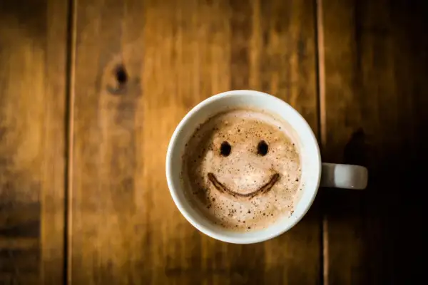 Tasse de café avec un visage souriant, une boisson qui ne fait pas grossir si consommée avec modération.