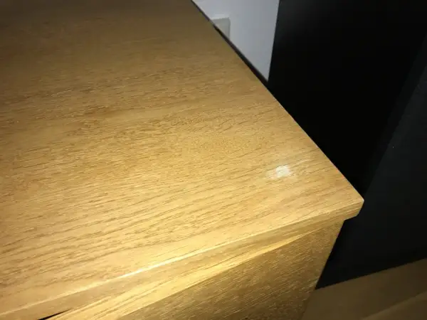 En träyta med tydlig ådring, kanske redo att slipa faner för en jämnare finish. En vit fläck syns på kanten.