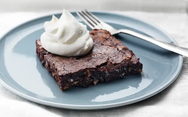 En saftig brownie med nötter, toppad med vispad grädde, redo att avnjutas. Perfekt för ett enkelt brownie recept.
