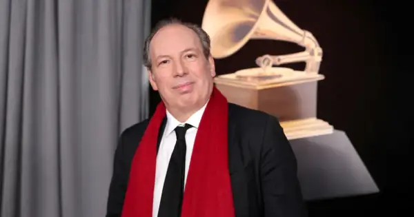Hans Zimmer, który napisał muzykę do filmu Gladiator, pozuje z czerwoną szarfą i statuetką Grammy.