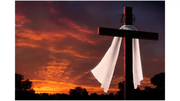 Kreuz mit Dornenkrone und Leichentuch vor dramatischem Sonnenuntergang. Ein Symbol für Karfreitag, den Feiertag der Besinnung.