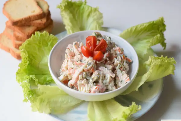 Deliciosa ensalada de cangrejo cremosa, servida con hojas de lechuga fresca y tostadas.