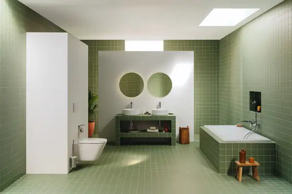 Moderno baño con azulejos verdes, doble lavabo, bañera y WC. Un espacio ideal para renovar el baño con estilo y funcionalidad.