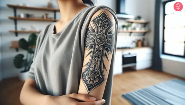 Un detallado tatuaje chicano brazo con una cruz ornamentada.