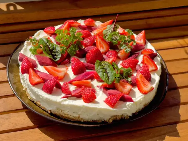 Ein köstlicher Erdbeer Rhabarber Kuchen mit frischen Früchten und Kräutern, bereit zum Genießen.