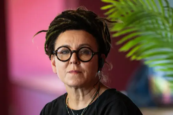 Olga Tokarczuk, wiek nieznany, w okularach i z dredami, słucha uważnie.