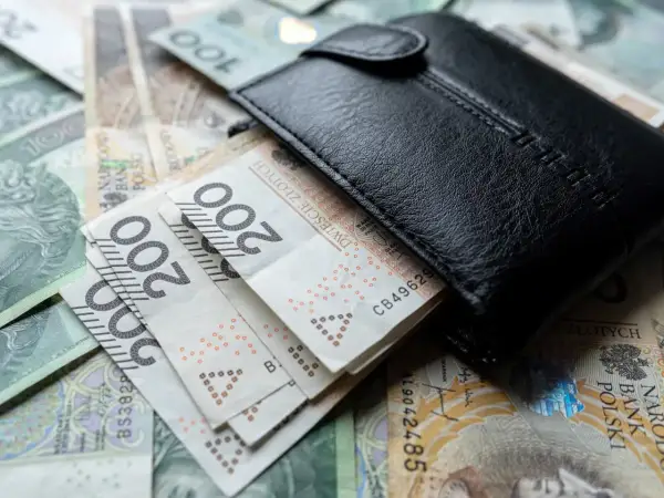 Czarny portfel na stosie polskich banknotów 200 zł. Czy to wystarczy na minimalne wynagrodzenie?
