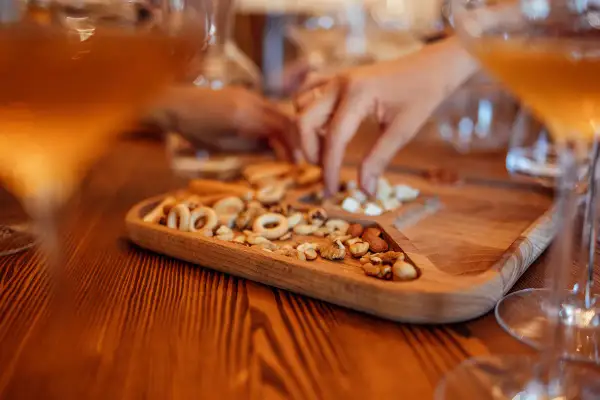 Un vassoio di legno con taralli e frutta secca, accanto a bicchieri di vino ambrato. Un momento di relax e gusto.