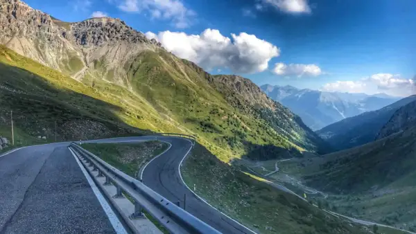 Kręta, górska stelvio droga wije się przez zielone zbocza Alp, prowadząc w głąb doliny.