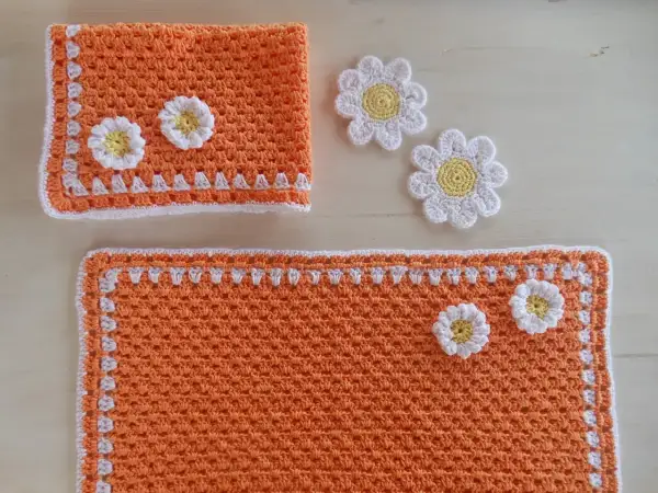 Tovagliette uncinetto schemi gratis: un set arancione con fiori bianchi e gialli, perfetto per decorare la tavola.