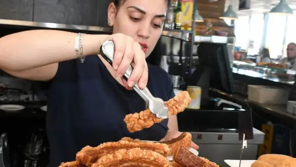 Camarera sirviendo crujiente chicharrón, perfecto para comer en carretera cerca de Zaragoza.