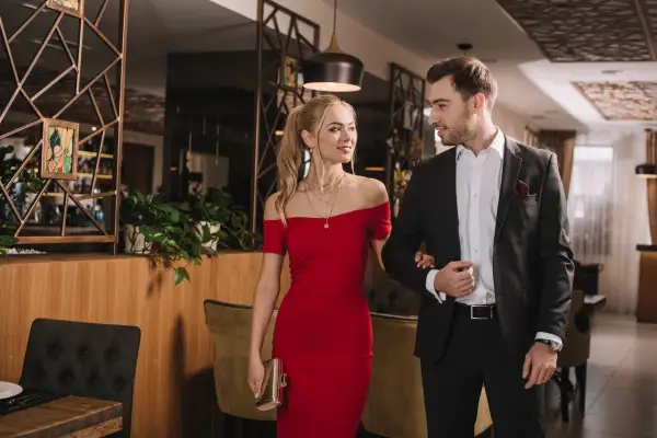 Para, ubrana w czerwoną sukienkę, i mężczyzna w garniturze, idealnie wpisują się w dress code cocktail.