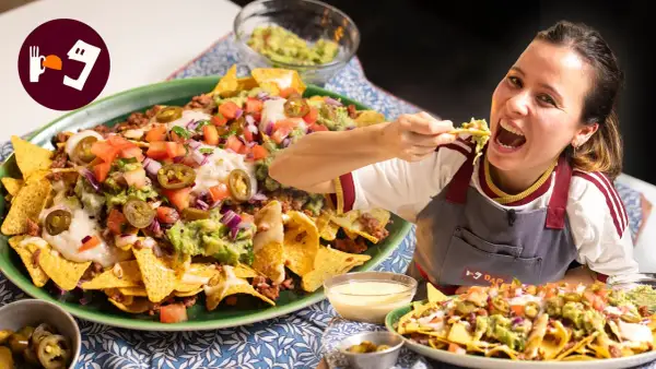 Una mujer disfruta de unos deliciosos nachos tex mex, cargados de carne, guacamole, queso y jalapeños.