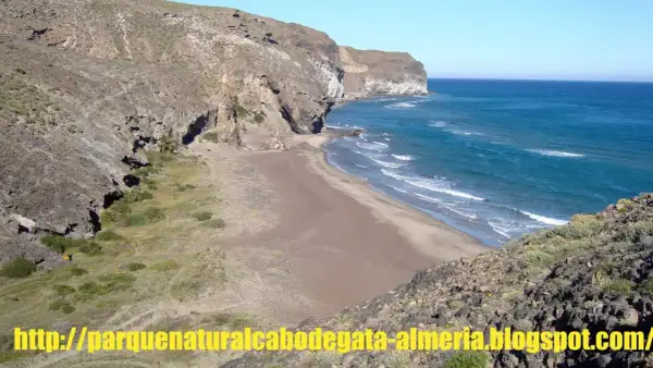Playa virgen de cala principe, Cabo de Gata, con acantilados rocosos y mar azul.