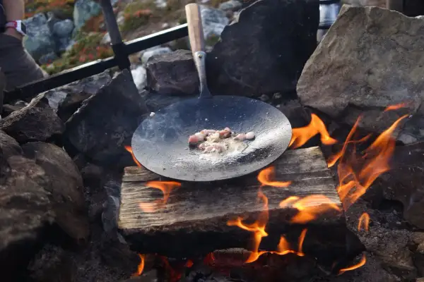Kolbulle smet fräser i stekpannan över öppen eld. En klassisk fjällmåltid tar form.