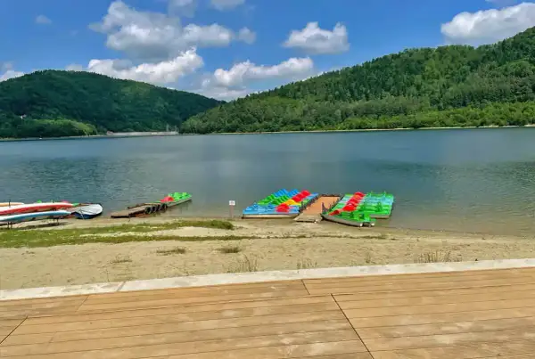 Kolorowe rowerki wodne i kajaki czekają nad spokojnym jeziorem w górach.
