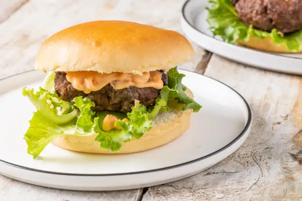Hamburger succulento con salsa, lattuga croccante e panino soffice, preparato in friggitrice ad aria.