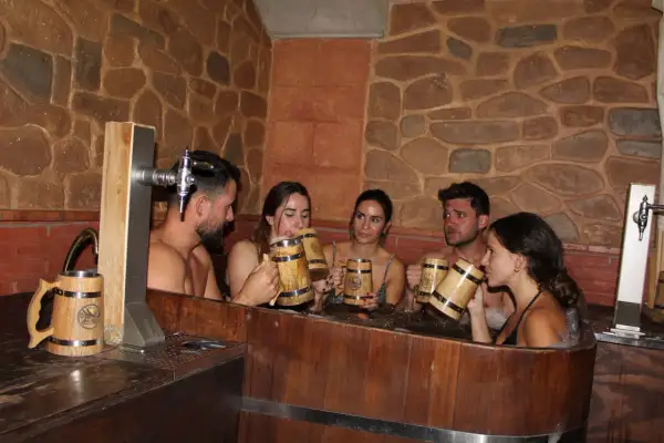 Amigos disfrutan de un relajante spa de cerveza en Valencia, brindando con jarras de madera.