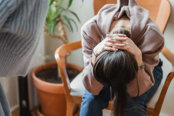 En person sitter med huvudet i händerna, kanske överväger effekterna av anafranil och alkohol.