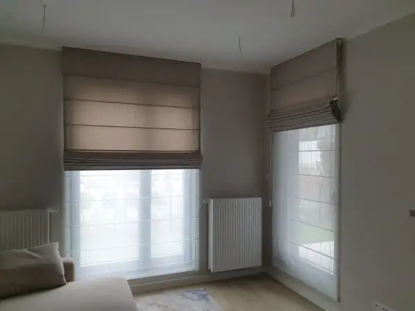 Eleganckie rolety rzymskie i zasłony tworzą przytulną atmosferę w pokoju.