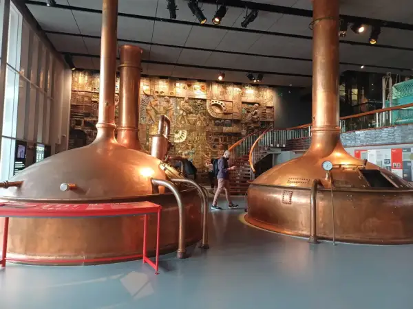Interior del museo Estrella Galicia con grandes cubas de cobre y un mural histórico.