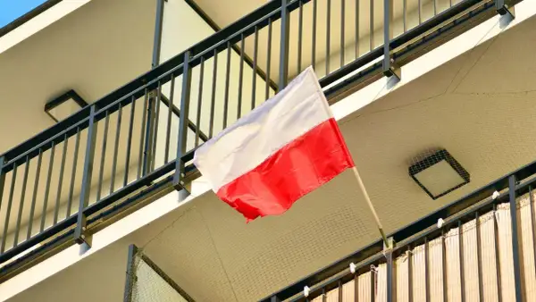 Polska flaga powiewa na balkonie. Biało-czerwone barwy symbolizują dumę i historię narodu.