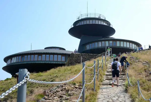 Wanderer steigen die Steintreppe zur Schneekoppe Seilbahn hinauf. Die futuristischen Gebäude auf dem Gipfel sind schon zu sehen.