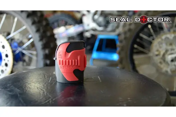Herramienta roja para reparar horquilla moto, con logo "Seal Doctor" al fondo.
