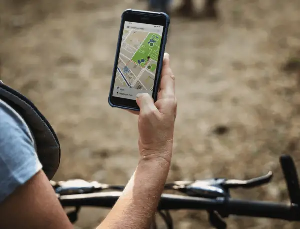 Rowerzysta sprawdza na telefonie mapę z trasą. Lokalizator GPS do roweru pomaga znaleźć drogę.