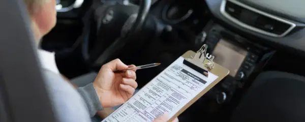 Persona revisa un formulario de solicitud de examen de manejo, preparándose para obtener su carnet coche automático.