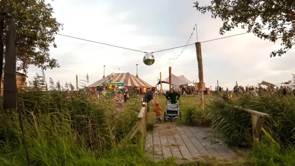 Ein buntes Zirkuszelt und Menschenmassen beim Calluna Festival. Eine Discokugel funkelt über dem Gelände.