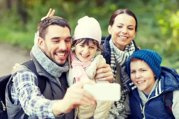 Familjen tar en glad selfie med Samsung i skogen. Pappa gör kaninöron bakom dotterns huvud.