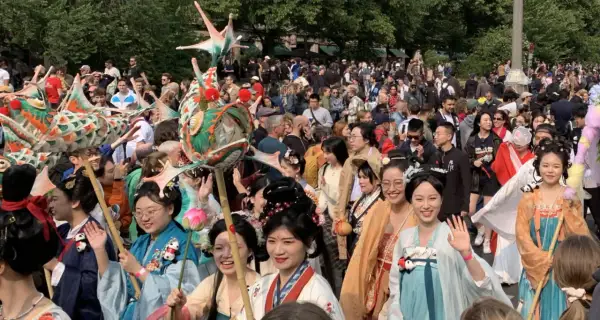 Bunte Drachenköpfe und Menschen in traditionellen Gewändern beleben den **Carnival Berlin**. Eine fröhliche Parade zieht durch die Menge.
