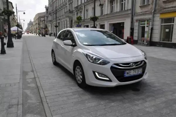 Biały Hyundai i30 1.4 benzyna na brukowanej ulicy w mieście.