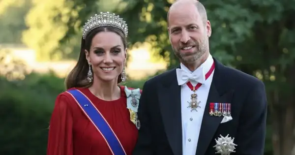 Kate i William w królewskich strojach, z diademem i medalami, uśmiechają się do zdjęcia.