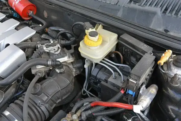 Silnik samochodu z widocznym zbiorniczkiem płynu hamulcowego i elementami układu elektrycznego. To właśnie serwo pomaga w hamowaniu.