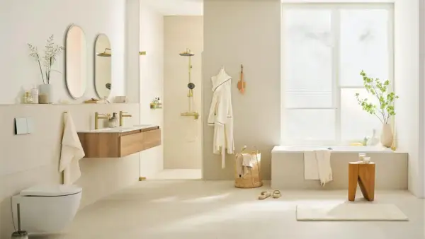 Helles, modernes Badezimmer mit cremefarbener Wandgestaltung. Goldene Armaturen und Duschkopf setzen Akzente. Die Farbgestaltung des kleinen Badezimmers ist beruhigend.