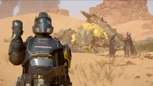 Helldivers 2 crossplay: żołnierze w pancerzach walczą z potworem na pustyni.
