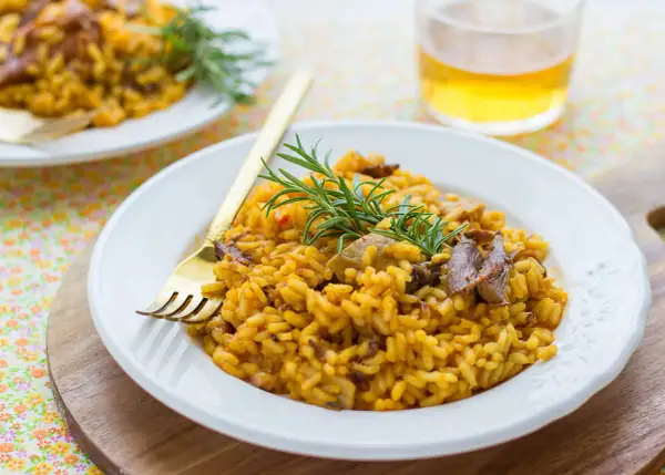 Delicioso arroz con secreto ibérico y setas, adornado con romero fresco. Un plato principal perfecto.
