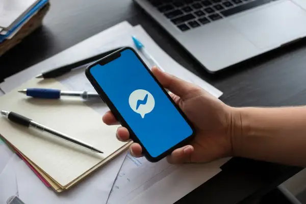 Dłoń trzyma smartfon z ikoną Messengera. Szukasz informacji, jak dezaktywować Messenger?
