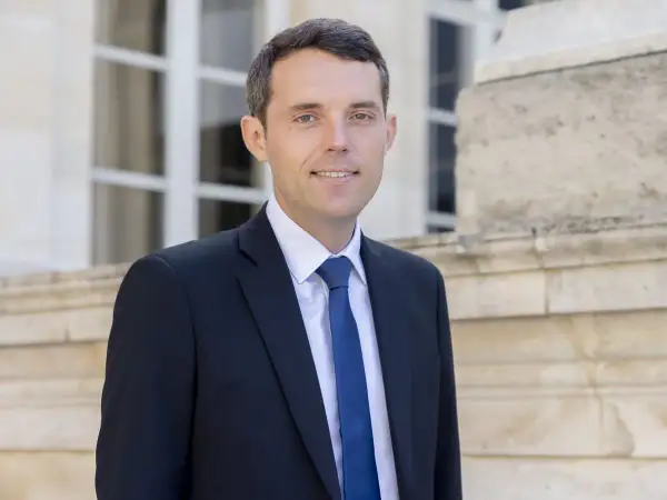 Alexandre Portier, souriant, en costume sombre, prêt pour son mariage.